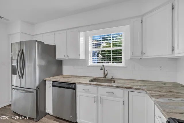 an empty room with wooden floor closet and windows