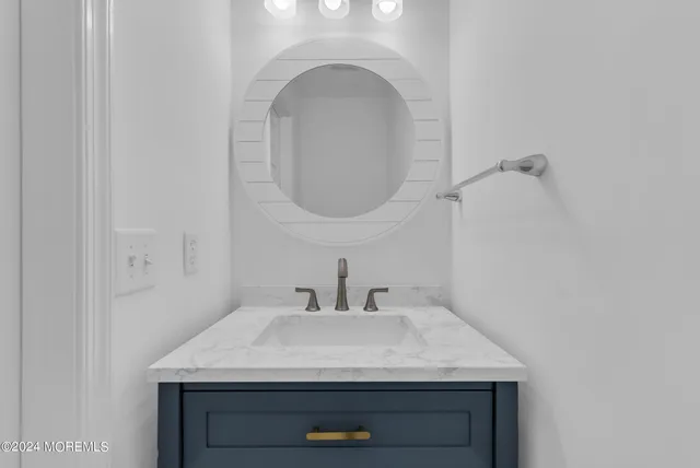 a bathroom with a granite countertop sink vanity mirror and toilet