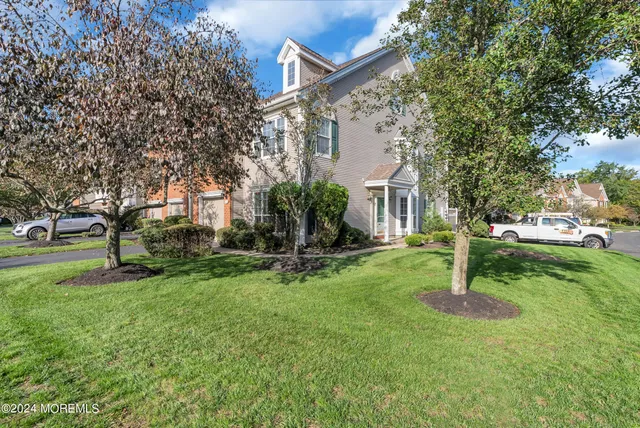 a view of a white house with a big yard and large trees