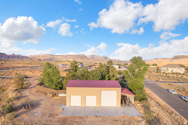 1440 West 100 South Virgin, UT 84779 - Photo 40 of 45 Detached workshop with a red metal roof, two roll-up garage doors, and a separate service door