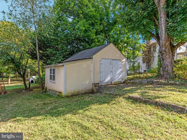 a view of a tiny house with a yard and large tree