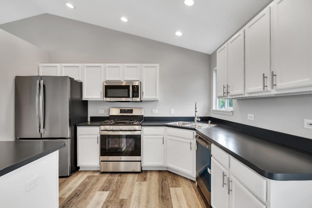303 Joshua Tree Harvard, IL 60033 - Photo 4 of 14 a kitchen with a sink a microwave a refrigerator and cabinets