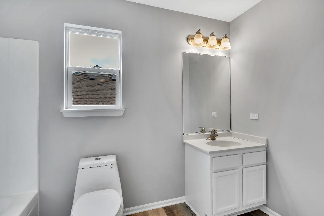 303 Joshua Tree Harvard, IL 60033 - Photo 6 of 14 a bathroom with a toilet sink vanity and mirror