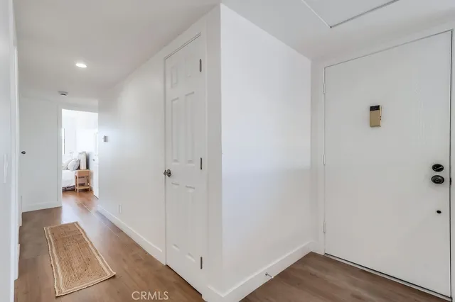 a view of a hallway with wooden floor and a bathroom