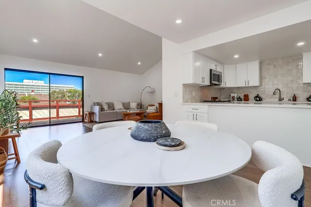 a kitchen with stainless steel appliances a dining table chairs and a large window