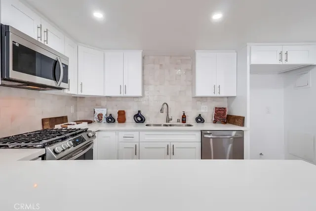 a kitchen with stainless steel appliances a sink a stove and cabinets