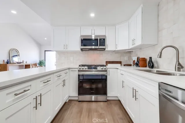 a kitchen with cabinets stainless steel appliances a sink and wooden floor