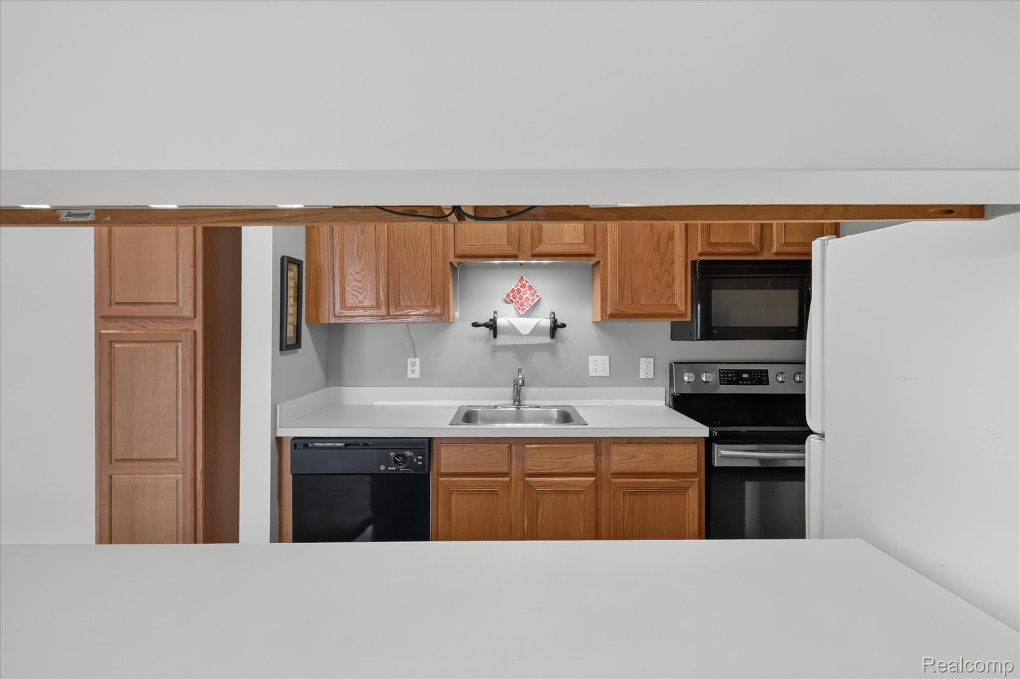 45720 Prairiegrass Court Belleville, MI 48111 - Photo 13 of 31 Kitchen featuring wood-finish cabinetry, a black dishwasher, and a black oven with stainless steel accents