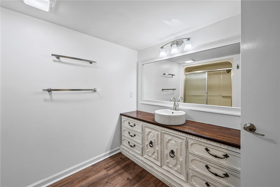 118 Beacon Ridge Circle Salem, SC 29676 - Photo 24 of 45 A well-lit bathroom features a striking vanity with an above-counter sink, complemented by a large mirror and warm wooden flooring.