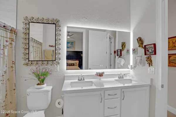 a spacious bathroom with a double vanity sink a mirror and a toilet