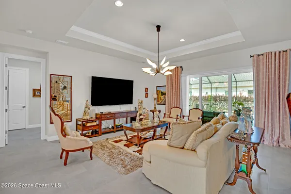 a living room with furniture a flat screen tv and a chandelier