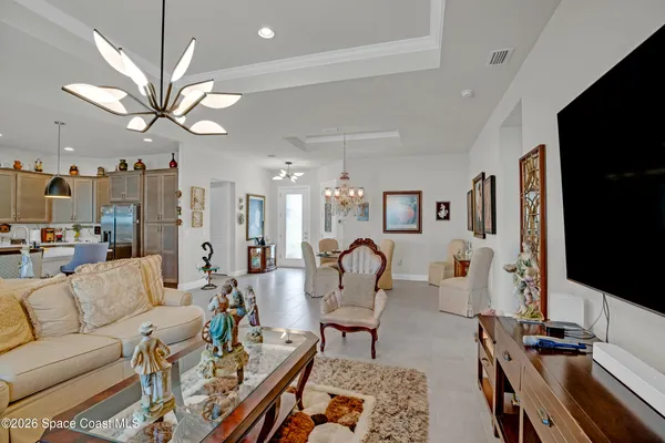 a living room with furniture a chandelier and a dining room