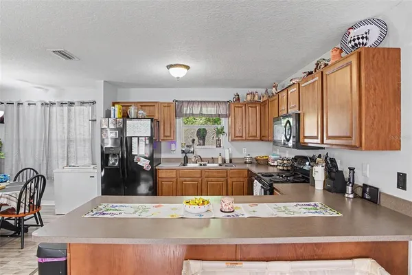 a view of a kitchen with kitchen island granite countertop a refrigerator stove top oven and sink