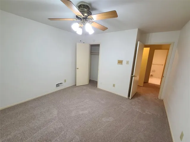 an empty room with a ceiling fan and a window