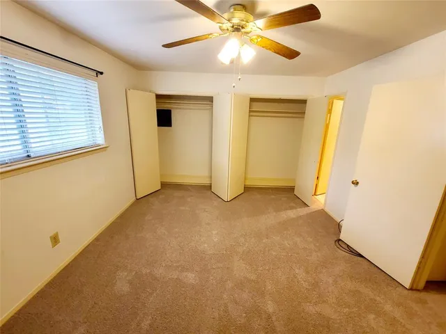 a view of an empty room with closet and a window