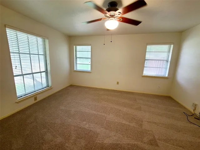 an empty room with windows and fan