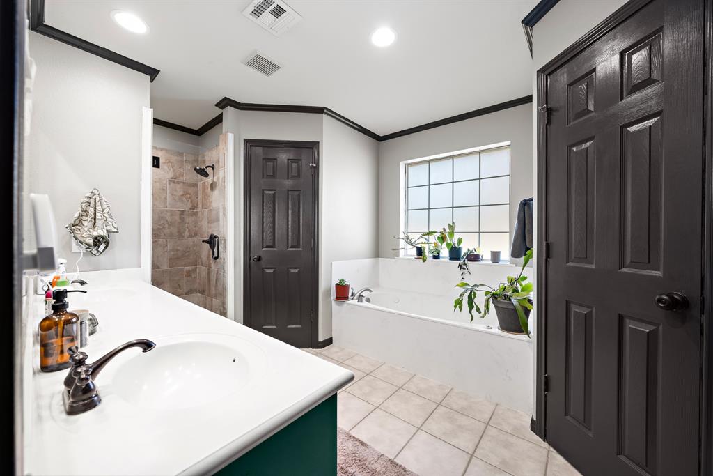 10512 Whitney Trace Drive Waco, TX 76708 - Photo 31 of 39 Spacious bathroom featuring a built-in soaking tub with a grid-patterned window, separate tiled shower with dark fixtures, and a vanity with an integrated sink and dark bronze faucet