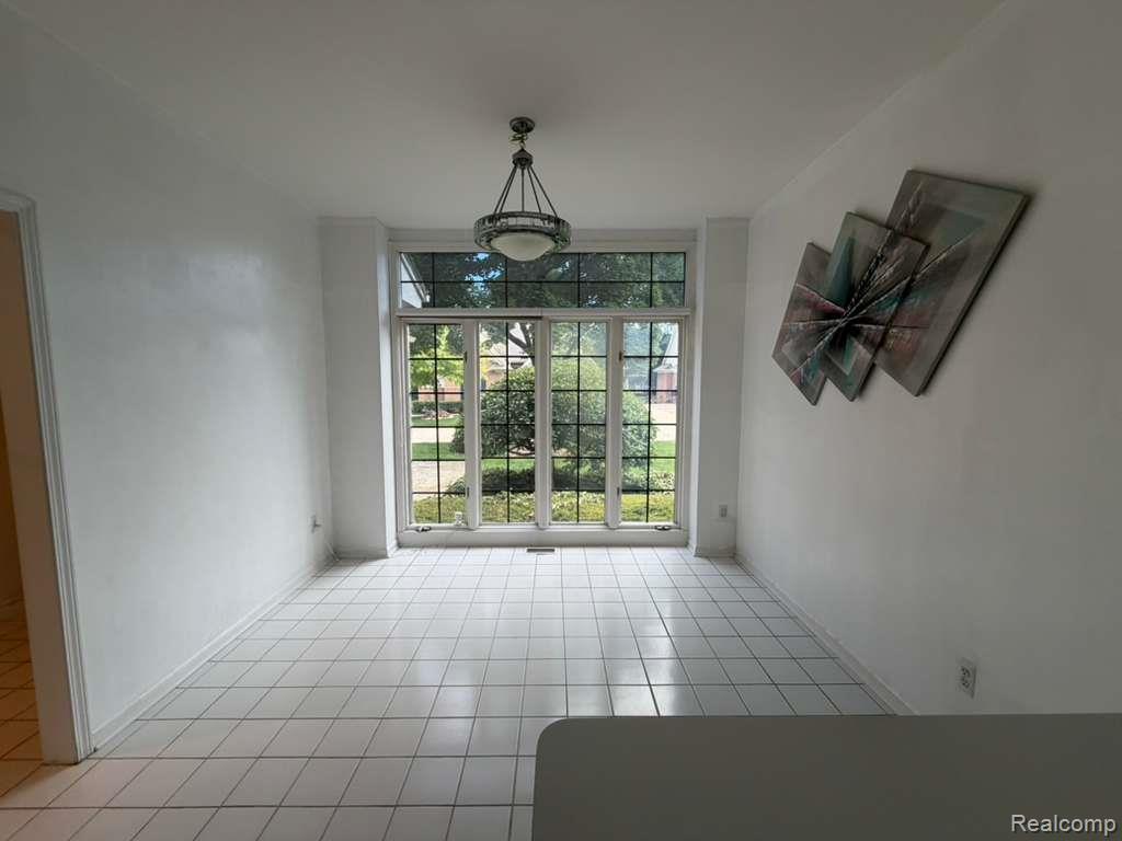 1154 Bluebird Drive Rochester, MI 48307 - Photo 14 of 34 Spacious room featuring a large leaded-glass bay window, white ceramic tile flooring, and a decorative ceiling light fixture