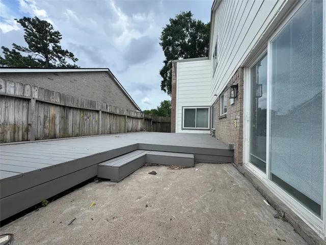 a view of backyard with large window and wooden fence