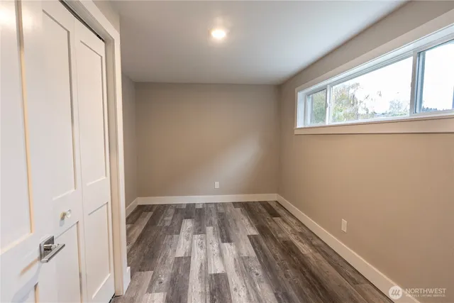 a view of hallway with window and wooden floor