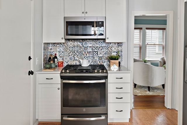 a kitchen with stainless steel appliances white cabinets and a stove top oven