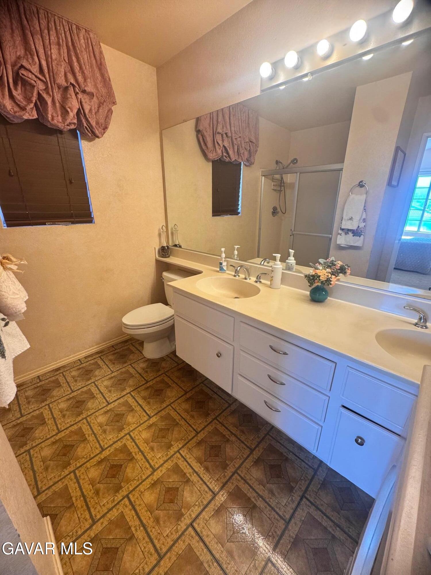 2309 Gregory Avenue Palmdale, CA 93550 - Photo 20 of 29 a bathroom with a double vanity sink a mirror and a toilet