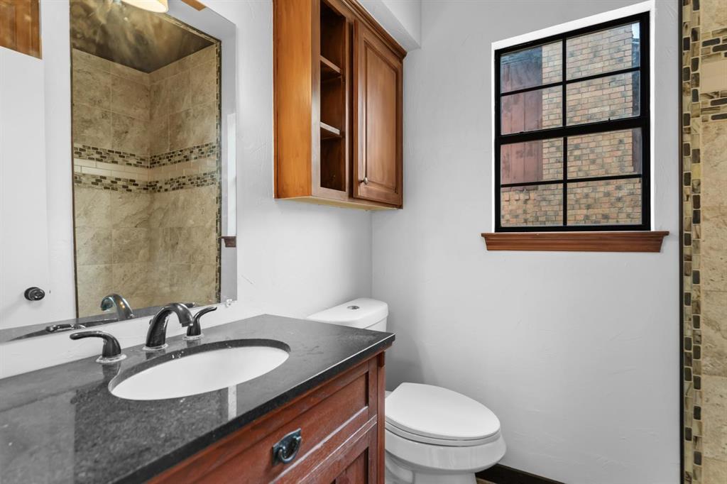 525 Pecan Lane Rowlett, TX 75089 - Photo 20 of 23 a bathroom with a granite countertop toilet a sink and a mirror