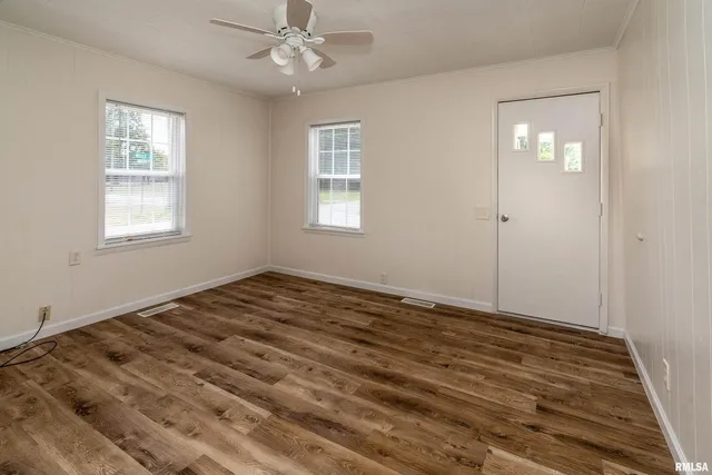a view of empty room with wooden floor and fan