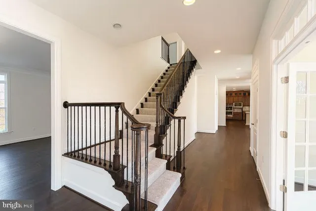a view of a hallway with wooden floor and stairs