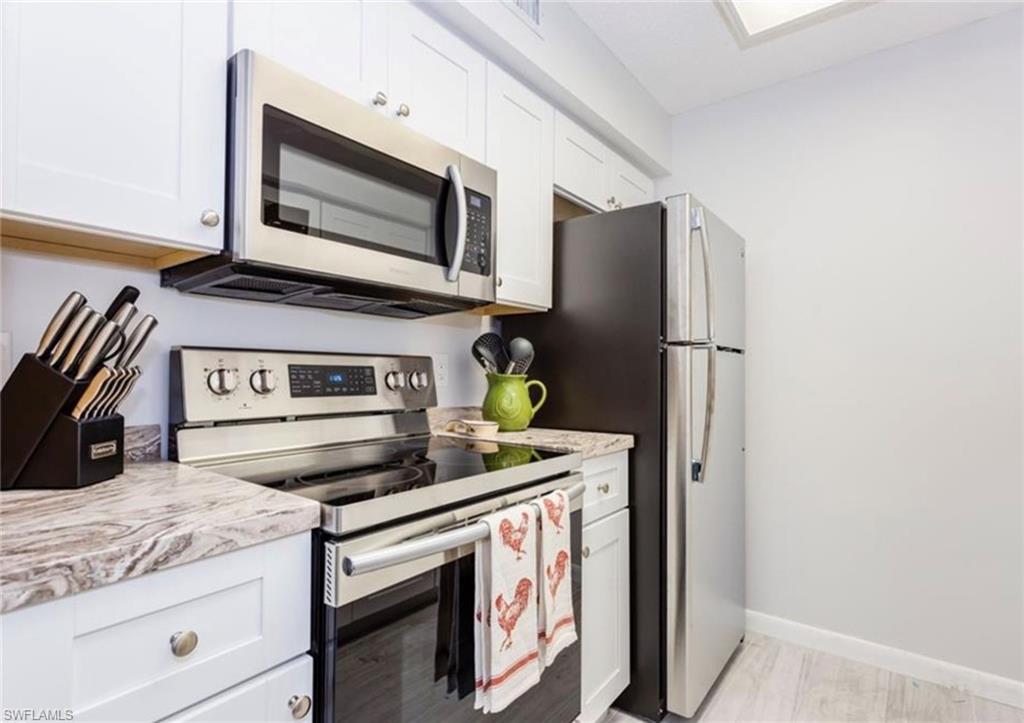 372 4th Avenue South, Unit 372 Naples, FL 34102 - Photo 2 of 14 Kitchen with stainless steel appliances and white cabinetry