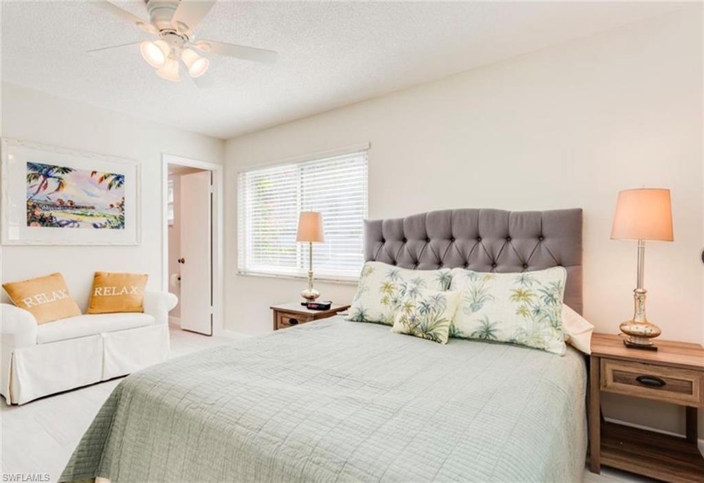 372 4th Avenue South, Unit 372 Naples, FL 34102 - Photo 7 of 14 Bedroom with light wood-style floors, a textured ceiling, a ceiling fan, and ensuite bath