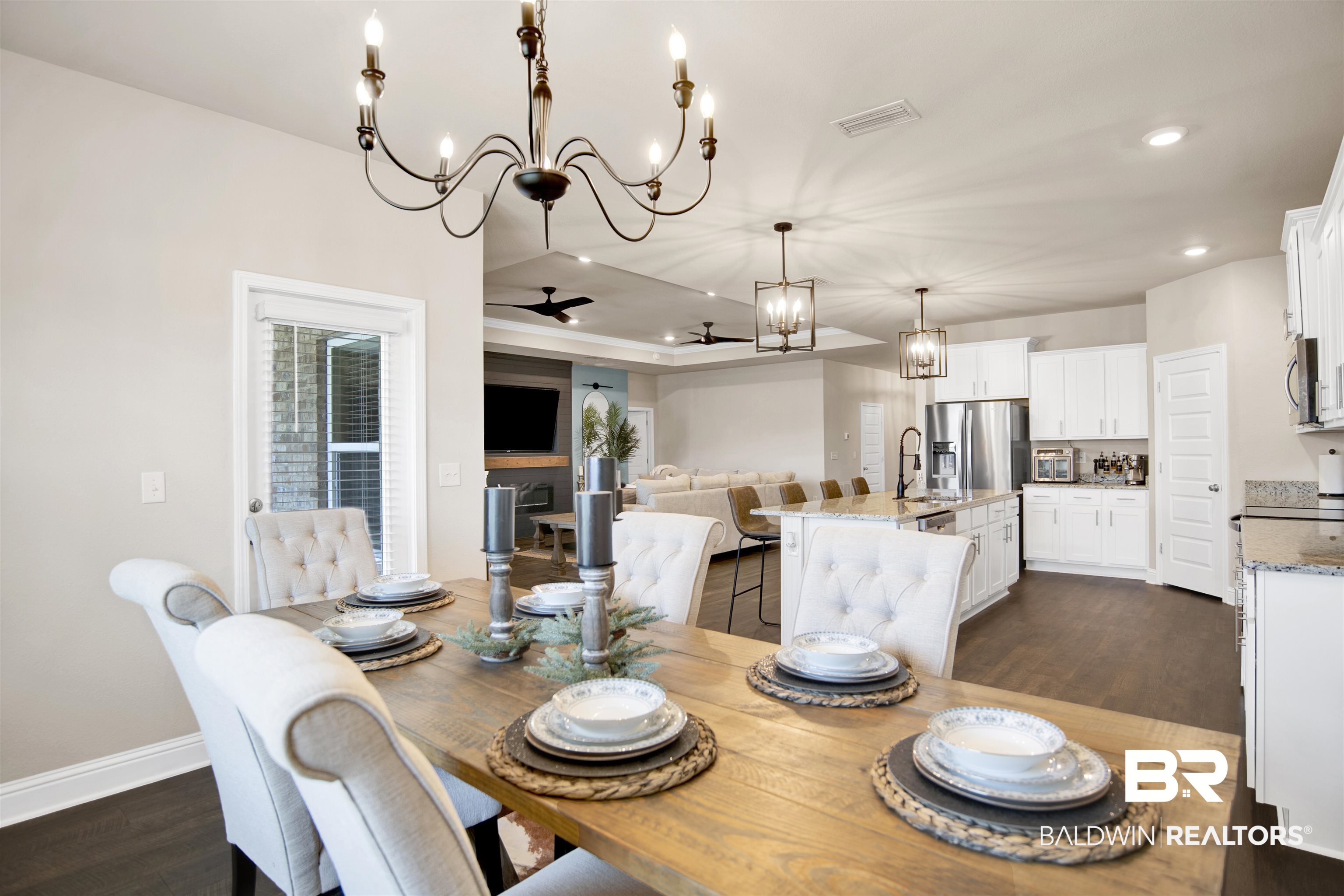 8493 Bronze Lane Foley, AL 36535 - Photo 16 of 38 Open-concept interior featuring wood-finish flooring, a kitchen with white cabinetry and a central island, and a dining area illuminated by a chandelier
