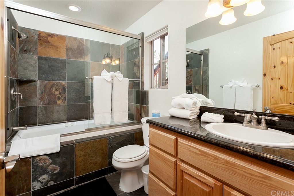 209 Rodeo Road Big Bear City, CA 92314 - Photo 31 of 39 a bathroom with a granite countertop sink a toilet a mirror and shower