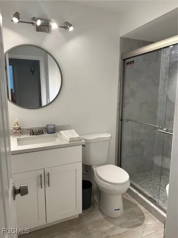 a bathroom with a toilet sink vanity granite and shower