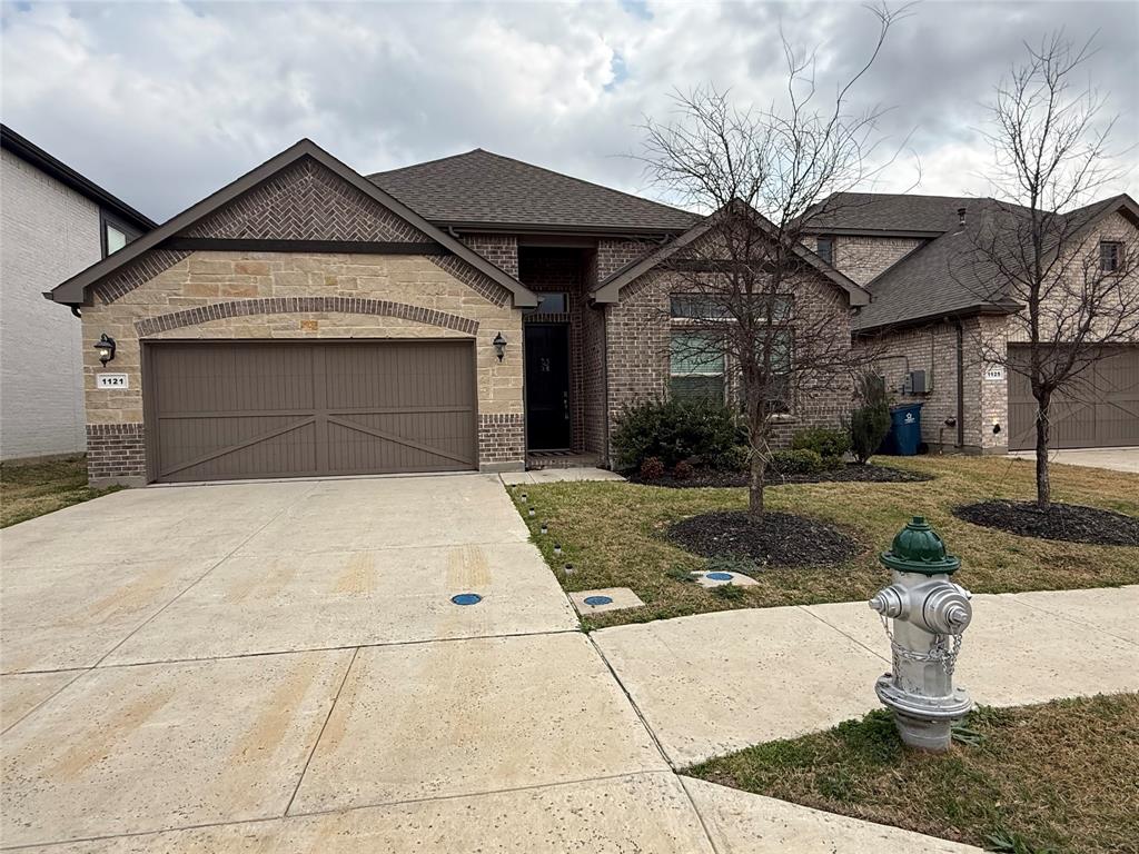 1121 Knightsbridge Road Argyle, TX 76226 - Photo 1 of 7 French provincial home with an attached garage, concrete driveway, roof with shingles, brick siding, and a front yard
