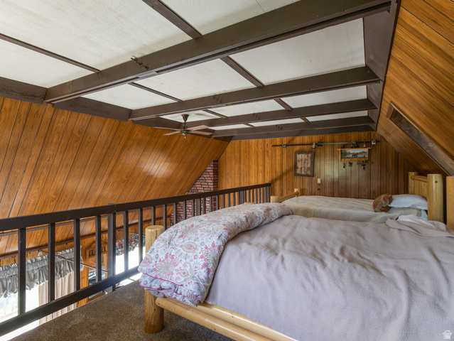4770 Pine Crest Road Evanston, UT 82930 - Photo 24 of 24 Wood-paneled loft area featuring a dark wood railing, exposed ceiling beams, a ceiling fan, and sloped wood-finish walls