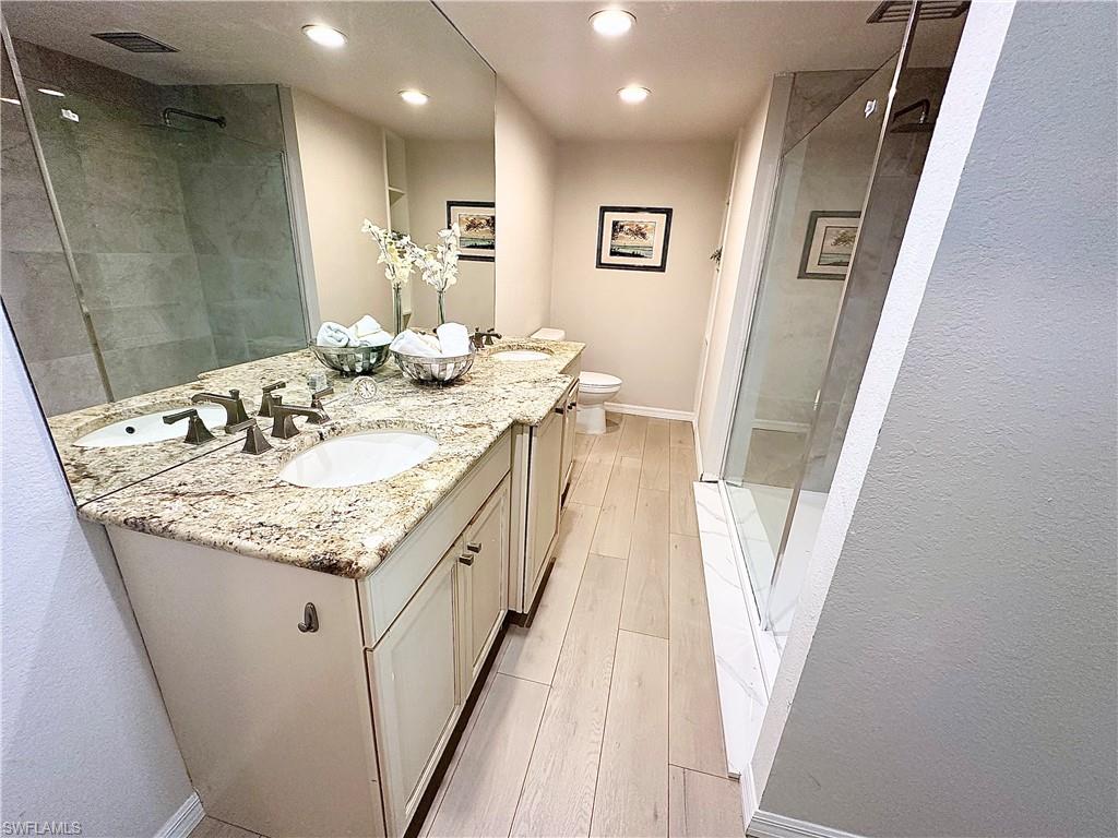 26261 Colony Road Bonita Springs, FL 34135 - Photo 8 of 31 Bathroom featuring vanity, toilet, a tile shower, and hardwood / wood-style flooring