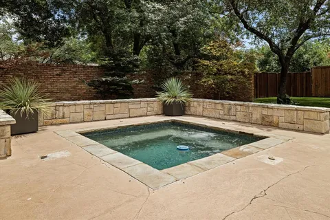 a view of a backyard with large trees and wooden fence