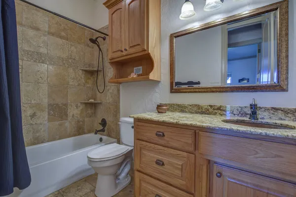 a bathroom with a granite countertop toilet sink and mirror