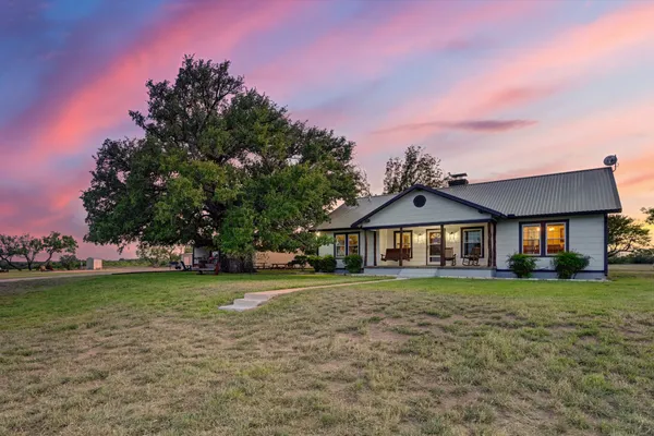 a front view of a house with a garden and trees