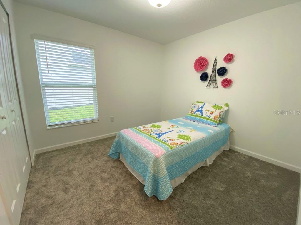 5010 Four Strand Court St. Cloud, FL 34772 - Photo 18 of 34 a bedroom with a bed and a table