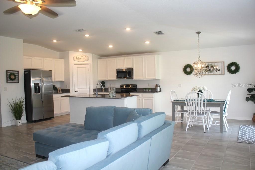 5010 Four Strand Court St. Cloud, FL 34772 - Photo 2 of 34 a kitchen with stainless steel appliances granite countertop a refrigerator a stove a sink a dining table and chairs with wooden floor