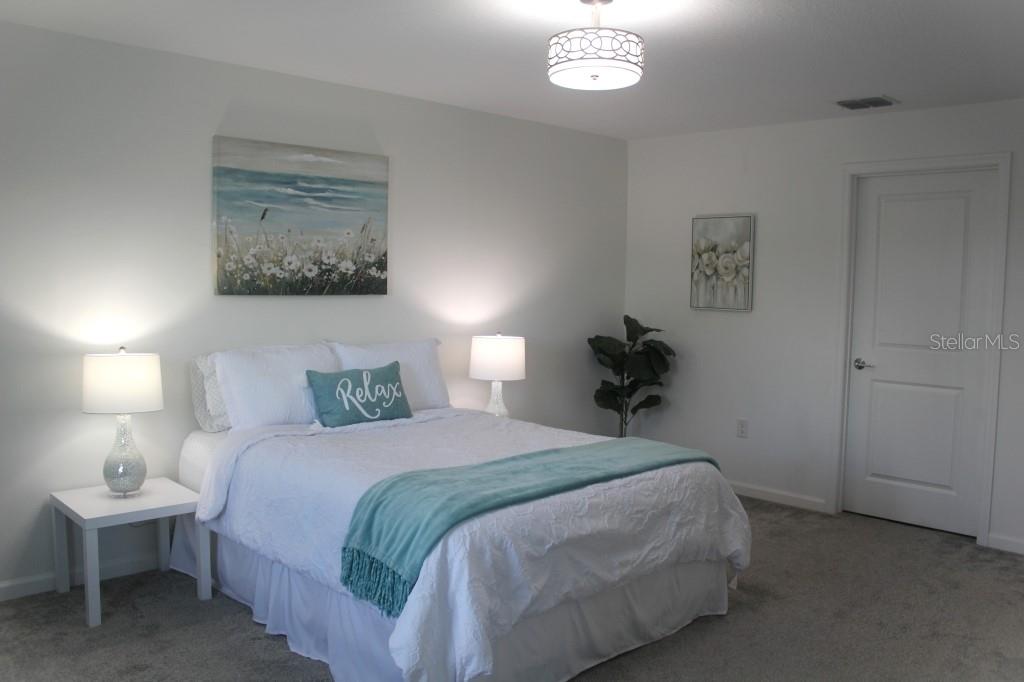 5010 Four Strand Court St. Cloud, FL 34772 - Photo 3 of 34 a bedroom with a bed and a lamp