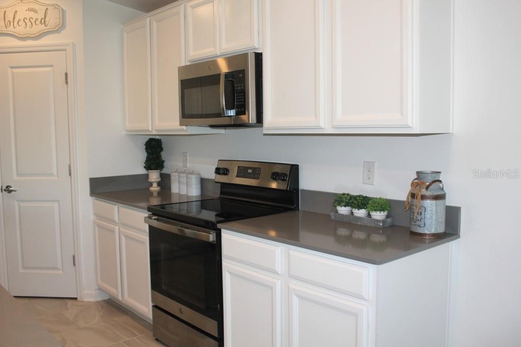 5010 Four Strand Court St. Cloud, FL 34772 - Photo 9 of 34 a kitchen with white cabinets and black appliances