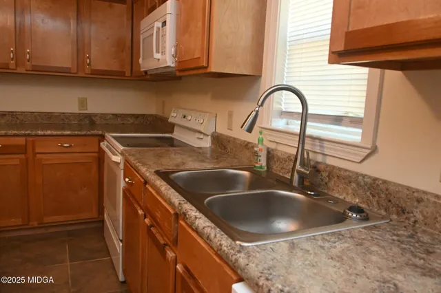 a kitchen with granite countertop a sink a stove and cabinets