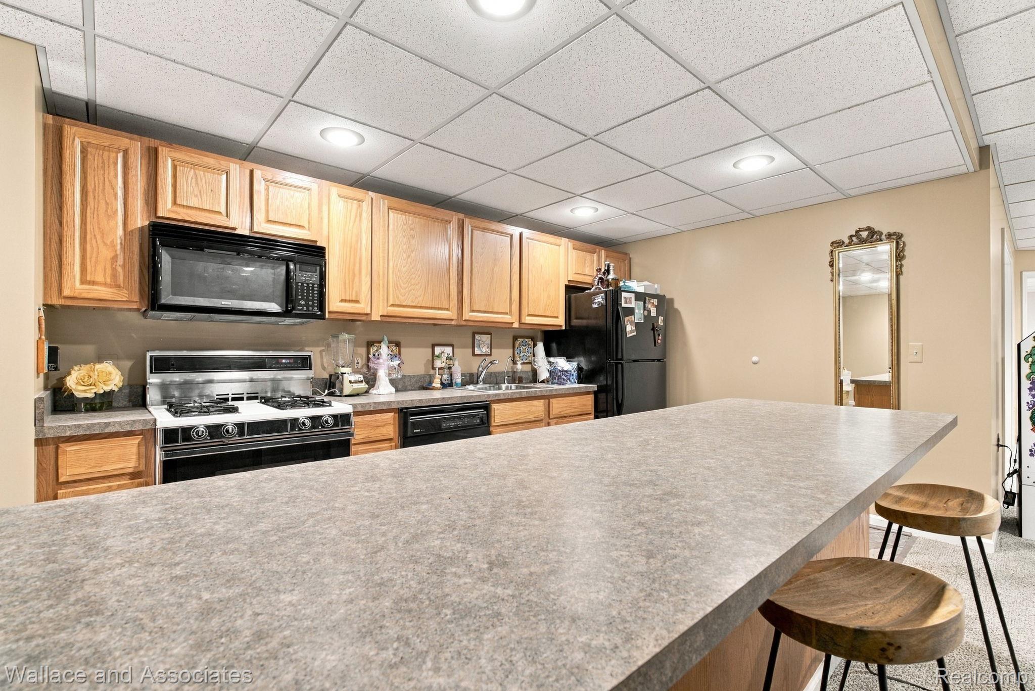 17076 27 Mile Road Ray, MI 48096 - Photo 41 of 63 Kitchenette featuring wood cabinetry, integrated microwave, black gas range, and a breakfast bar with solid surface countertop