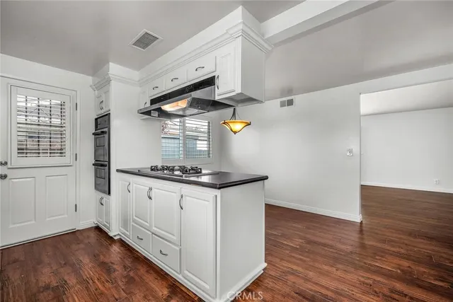 a kitchen with granite countertop a stove and a wooden floors