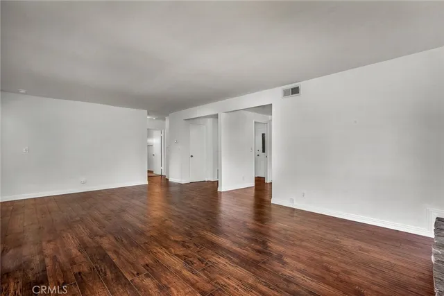 a view of an empty room with wooden floor and closet
