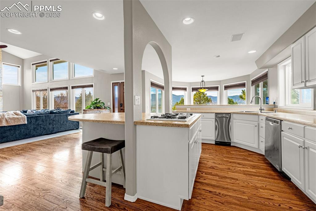 18475 Lower Lake Road Monument, CO 80132 - Photo 17 of 50 a kitchen with stainless steel appliances a sink a stove a refrigerator cabinets and a dining table with wooden floor