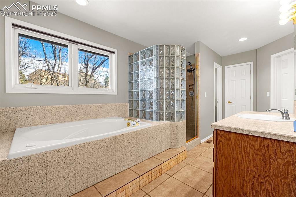 18475 Lower Lake Road Monument, CO 80132 - Photo 28 of 50 a bathroom with a tub a sink and glass door